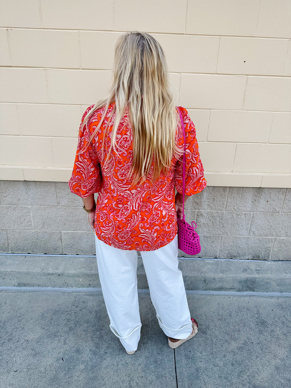 Pink and orange paisley print blouse with frilled tie neckline and three-quarter peasant sleeves against a neutral background