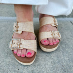 Raffia wedge sandal with slide-on design, dual straps, rhinestone buckles, and gold hardware embellishments