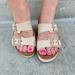 Raffia wedge sandal with slide-on design, dual straps, rhinestone buckles, and gold hardware embellishments