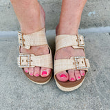 Raffia wedge sandal with slide-on design, dual straps, rhinestone buckles, and gold hardware embellishments