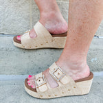 Raffia wedge sandal with slide-on design, dual straps, rhinestone buckles, and gold hardware embellishments