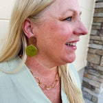Statement earrings featuring a pistachio green base with gold accents, displayed on a neutral background for a pop of color