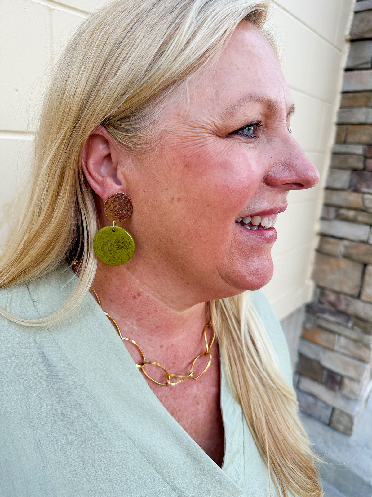 Statement earrings featuring a pistachio green base with gold accents, displayed on a neutral background for a pop of color