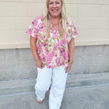 Pink floral babydoll top with ruffle collar, short sleeves, and a tie-neck detail, styled for a soft and feminine look.