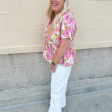 Pink floral babydoll top with ruffle collar, short sleeves, and a tie-neck detail, styled for a soft and feminine look.
