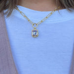 Gold-tone necklace with emerald-cut crystal pendant framed by a ball chain halo on a chunky paperclip chain.