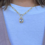 Gold-tone necklace with emerald-cut crystal pendant framed by a ball chain halo on a chunky paperclip chain.
