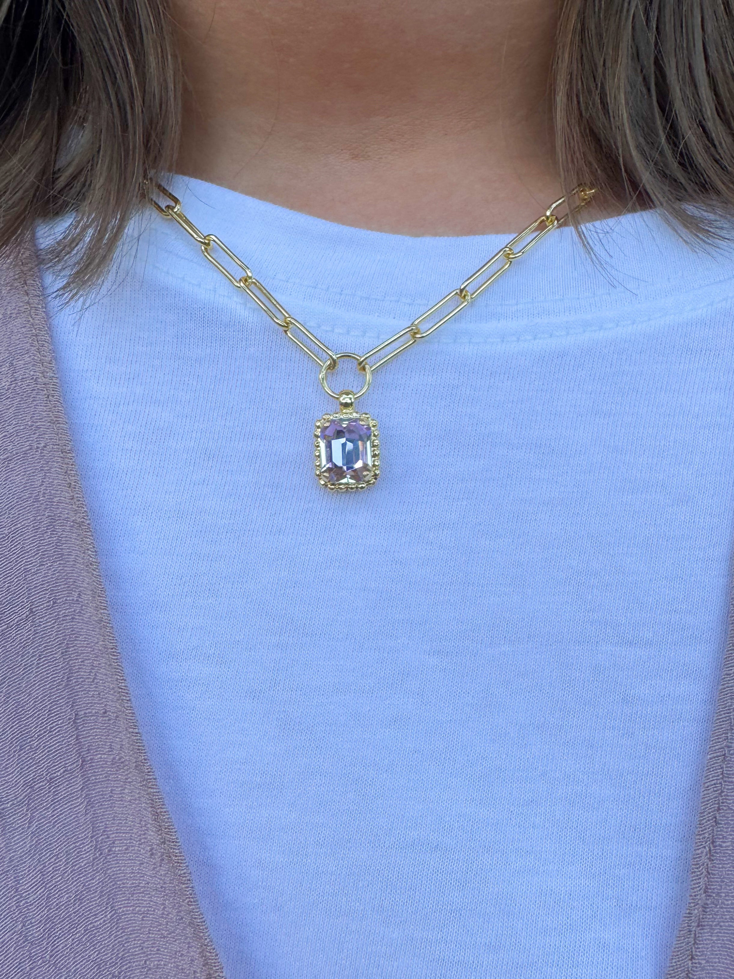 Gold-tone necklace with emerald-cut crystal pendant framed by a ball chain halo on a chunky paperclip chain.