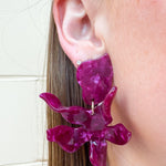 Oversized floral-shaped drop earrings in a pearlized dark red and purple color.