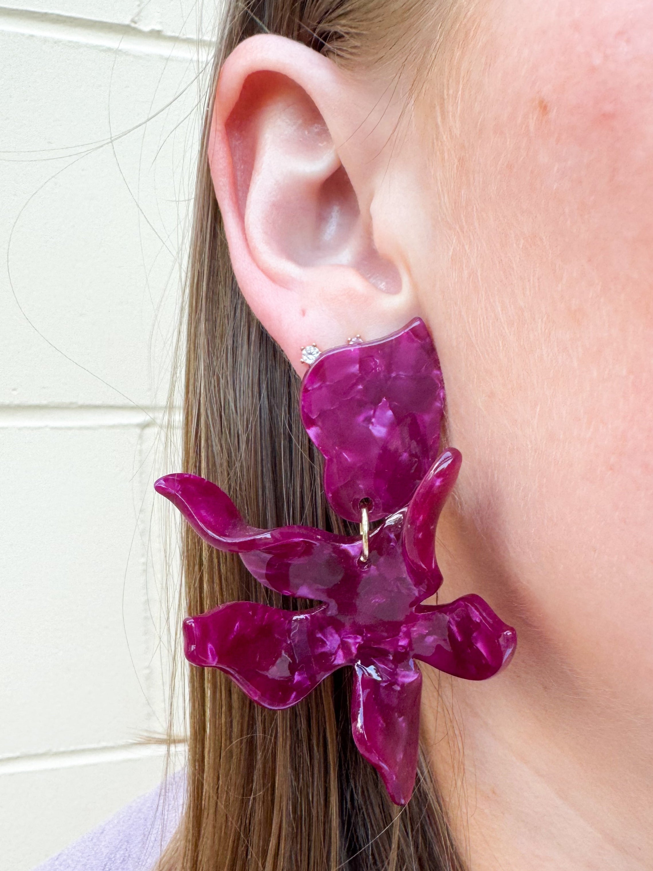 Oversized floral-shaped drop earrings in a pearlized dark red and purple color.