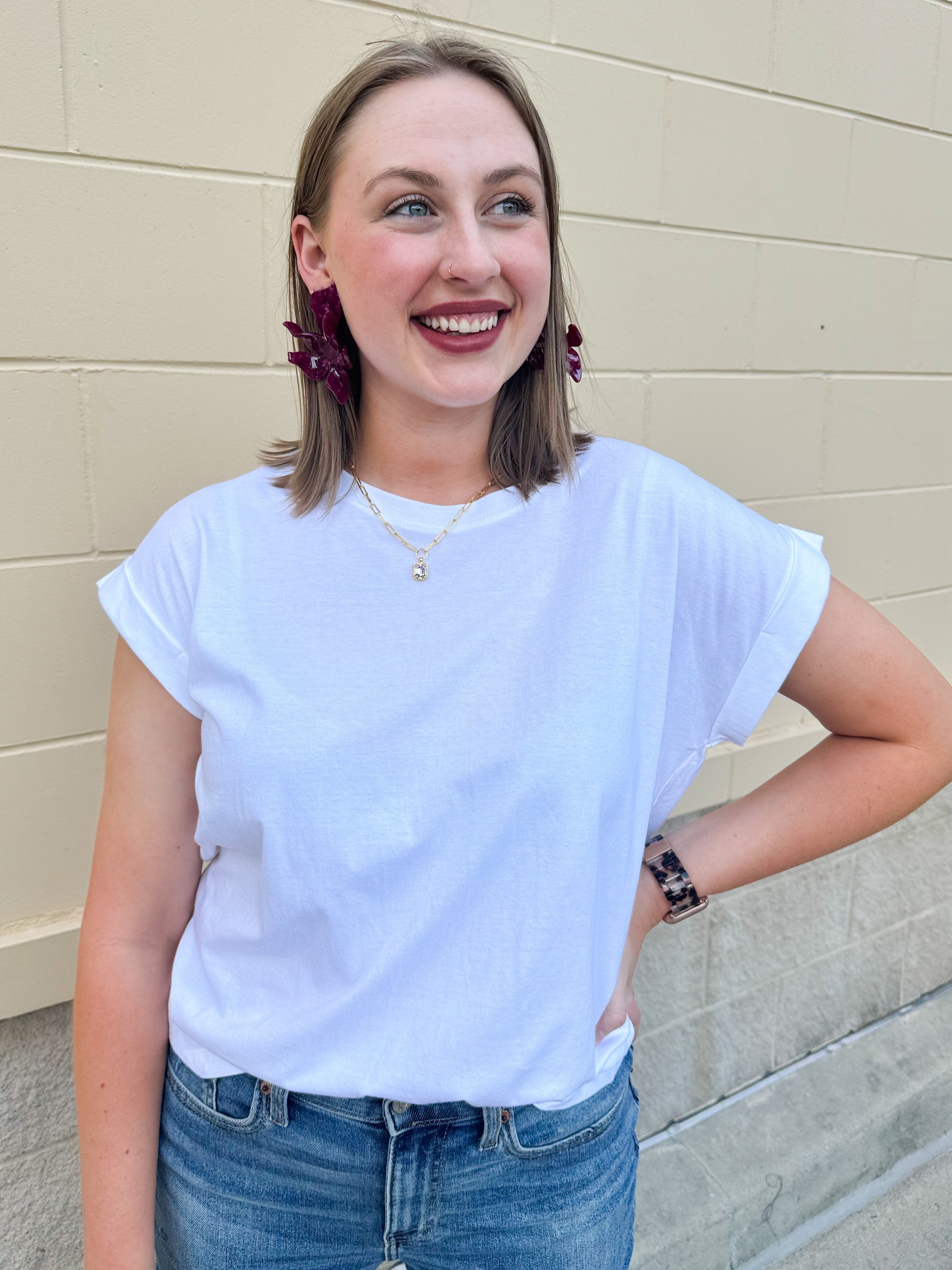 White rolled sleeve tee displayed on hanger or model, showing relaxed fit and classic style.