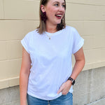 White rolled sleeve tee displayed on hanger or model, showing relaxed fit and classic style.