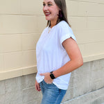 White rolled sleeve tee displayed on hanger or model, showing relaxed fit and classic style.