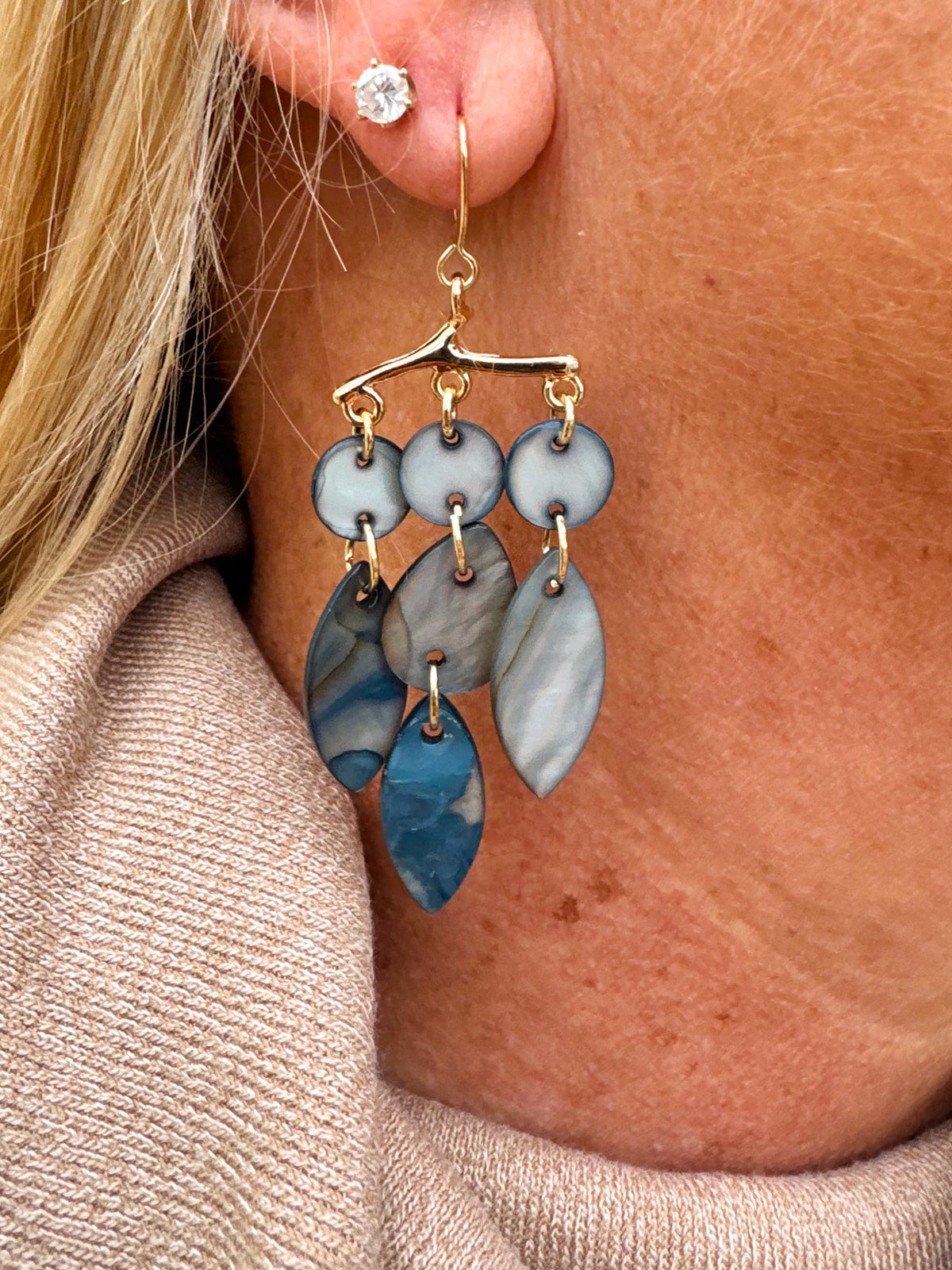 A pair of dangling mobile art shell earrings with various shades of blue and gold tones.