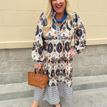 Tiered midi dress in fall blues, creams, and browns with ruffled collar and button-down placket.
