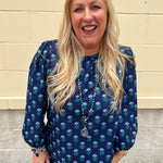 Blue floral print blouse with jewel neckline, back keyhole, and elastic puff sleeves.