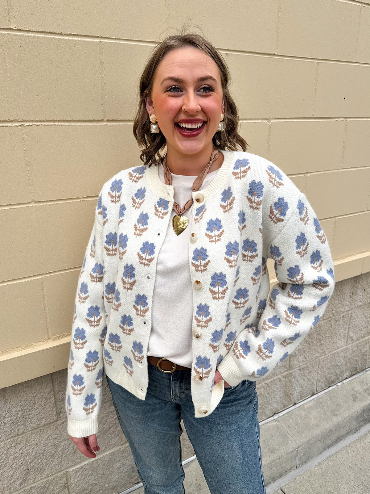 Cream floral jacquard cardigan with blue flowers, button-up front, long sleeves, and crewneck style.