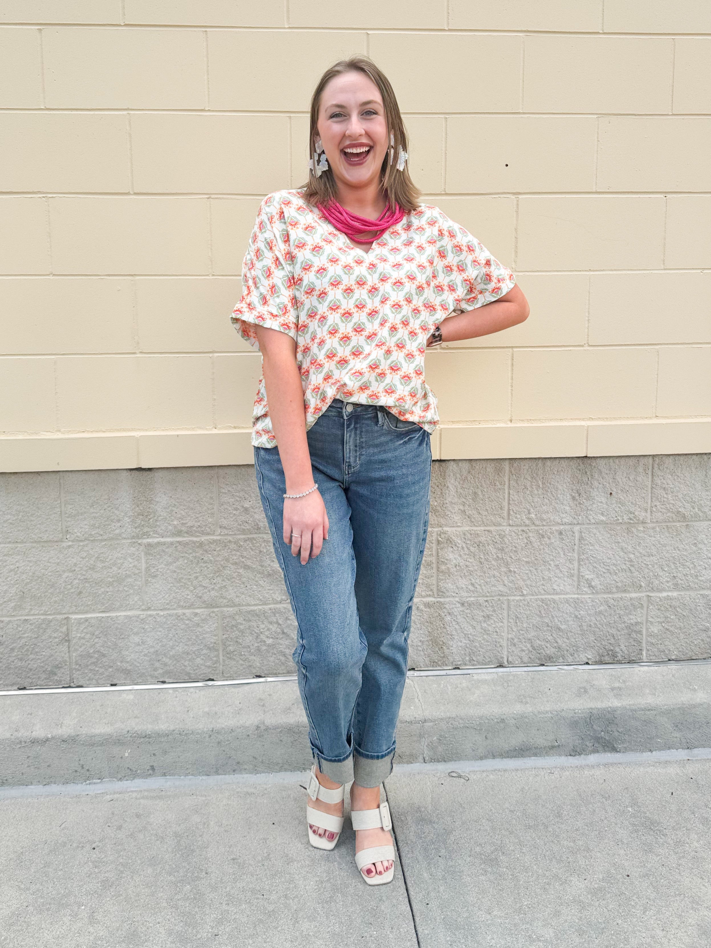 Bright floral v-neck top with dolman sleeves and drop shoulder design, styled for a relaxed and feminine look.