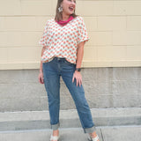 Bright floral v-neck top with dolman sleeves and drop shoulder design, styled for a relaxed and feminine look.