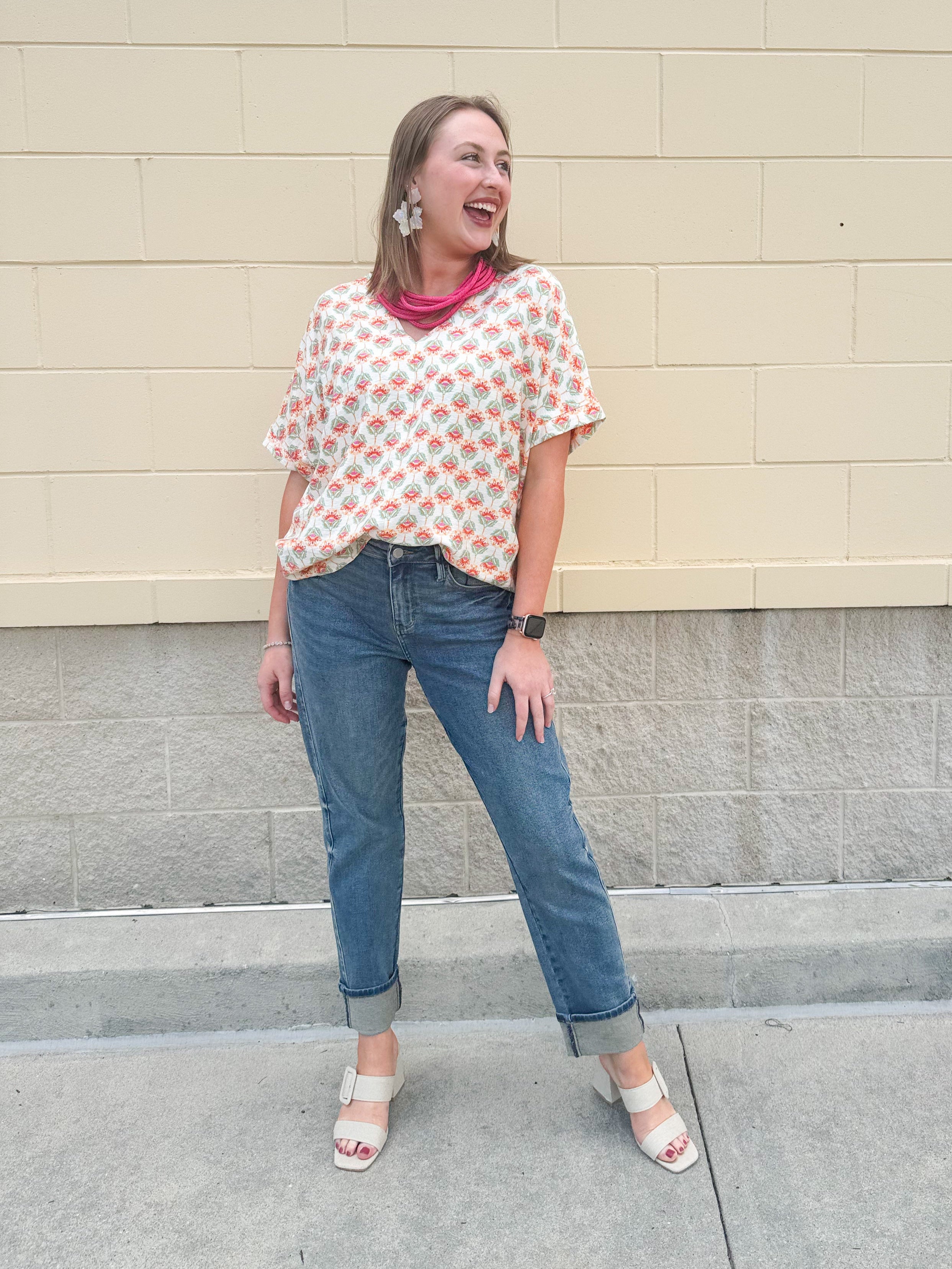 Bright floral v-neck top with dolman sleeves and drop shoulder design, styled for a relaxed and feminine look.