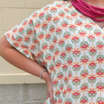 Bright floral v-neck top with dolman sleeves and drop shoulder design, styled for a relaxed and feminine look.
