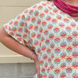Bright floral v-neck top with dolman sleeves and drop shoulder design, styled for a relaxed and feminine look.