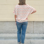 Bright floral v-neck top with dolman sleeves and drop shoulder design, styled for a relaxed and feminine look.