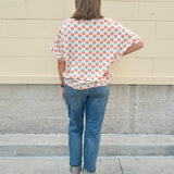 Bright floral v-neck top with dolman sleeves and drop shoulder design, styled for a relaxed and feminine look.