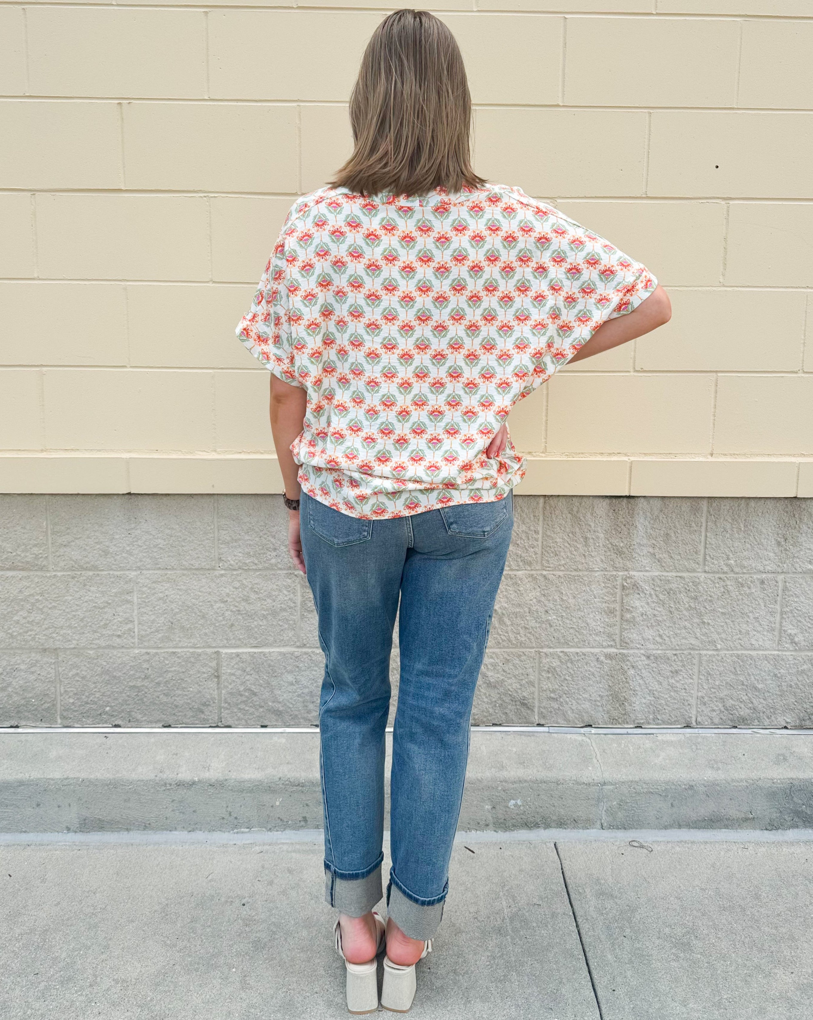 Bright floral v-neck top with dolman sleeves and drop shoulder design, styled for a relaxed and feminine look.