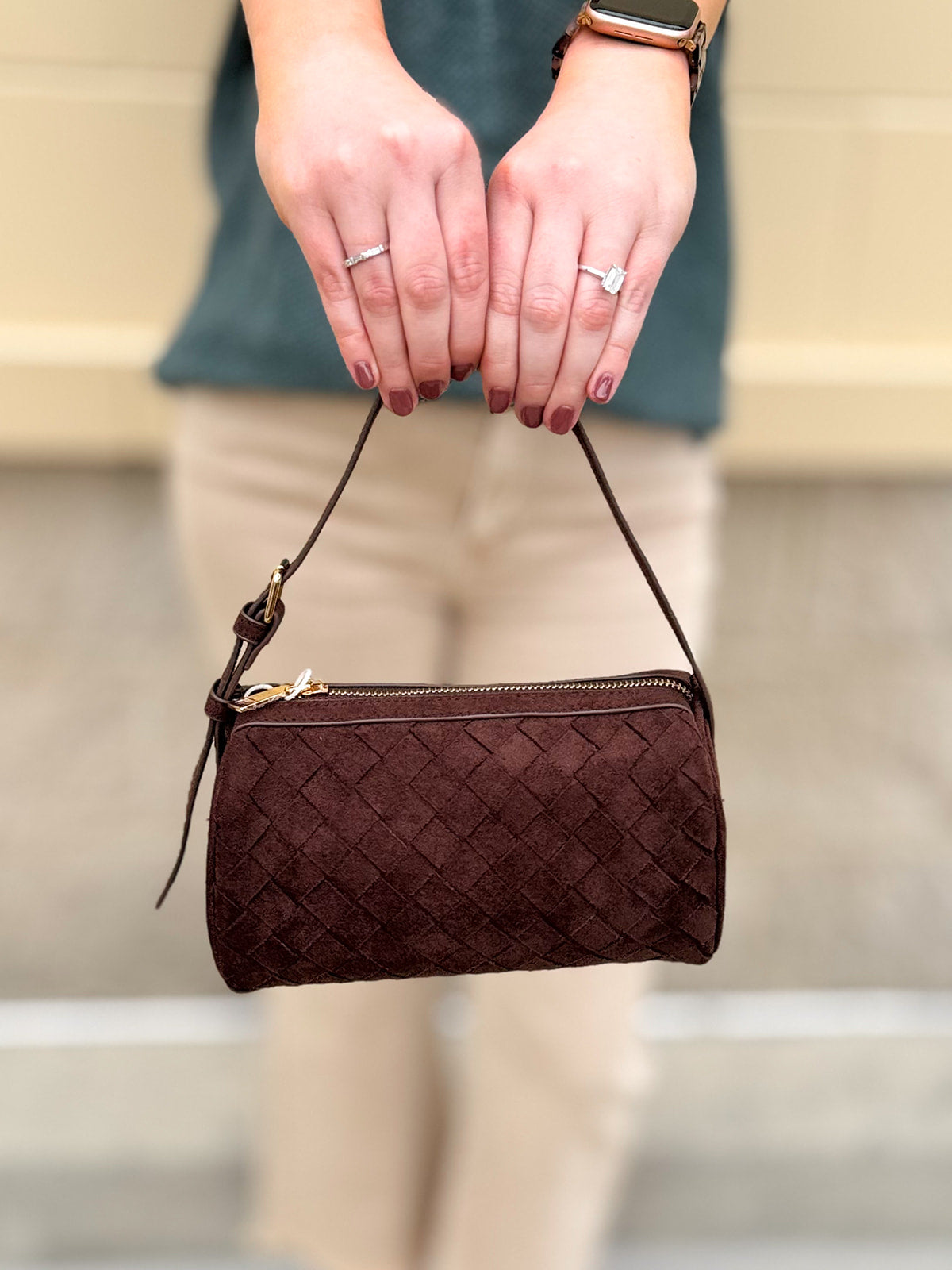 Chocolate brown cylinder-shaped shoulder bag with adjustable buckle strap and zip closure.