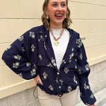 Navy embroidered long sleeve Jacket top with hood, cinched waist, and front pockets styled for fall.