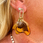 Quail feather tassel statement earrings with speckled feathers and soft tassels, displayed on a neutral background