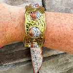 Gold cuff bracelet woven with geometric black-and-white scarf featuring a brown border; ties together for a bold yet feminine accessory.