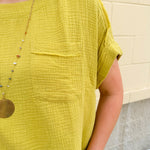 Mustard oversized ribbed top with front pocket, drop shoulders, and raw frayed hemline