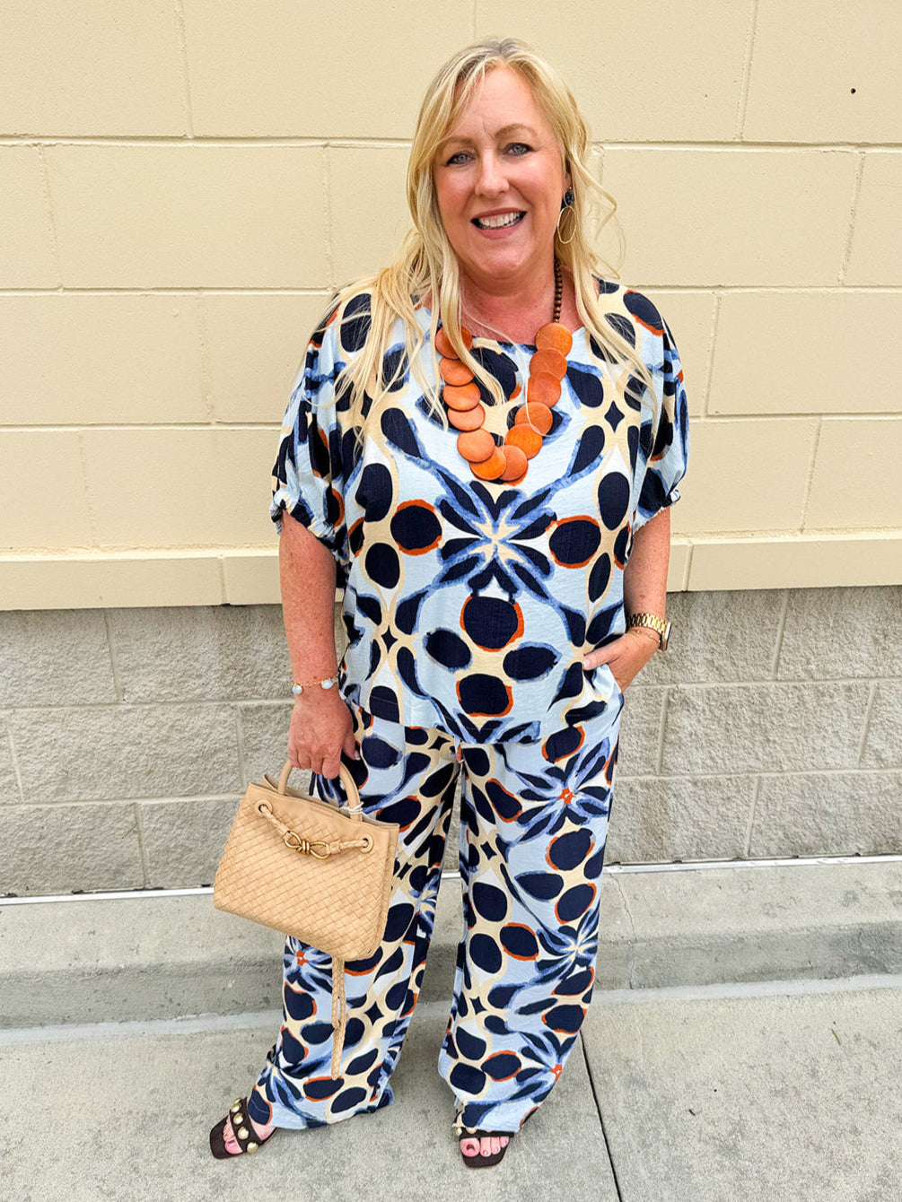 Printed short sleeve top in light blue with colorful indigo, orange, and yellow pattern, featuring a boat neck and relaxed A-line shape