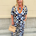 Printed short sleeve top in light blue with colorful indigo, orange, and yellow pattern, featuring a boat neck and relaxed A-line shape