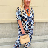 Printed short sleeve top in light blue with colorful indigo, orange, and yellow pattern, featuring a boat neck and relaxed A-line shape