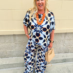 Printed short sleeve top in light blue with colorful indigo, orange, and yellow pattern, featuring a boat neck and relaxed A-line shape
