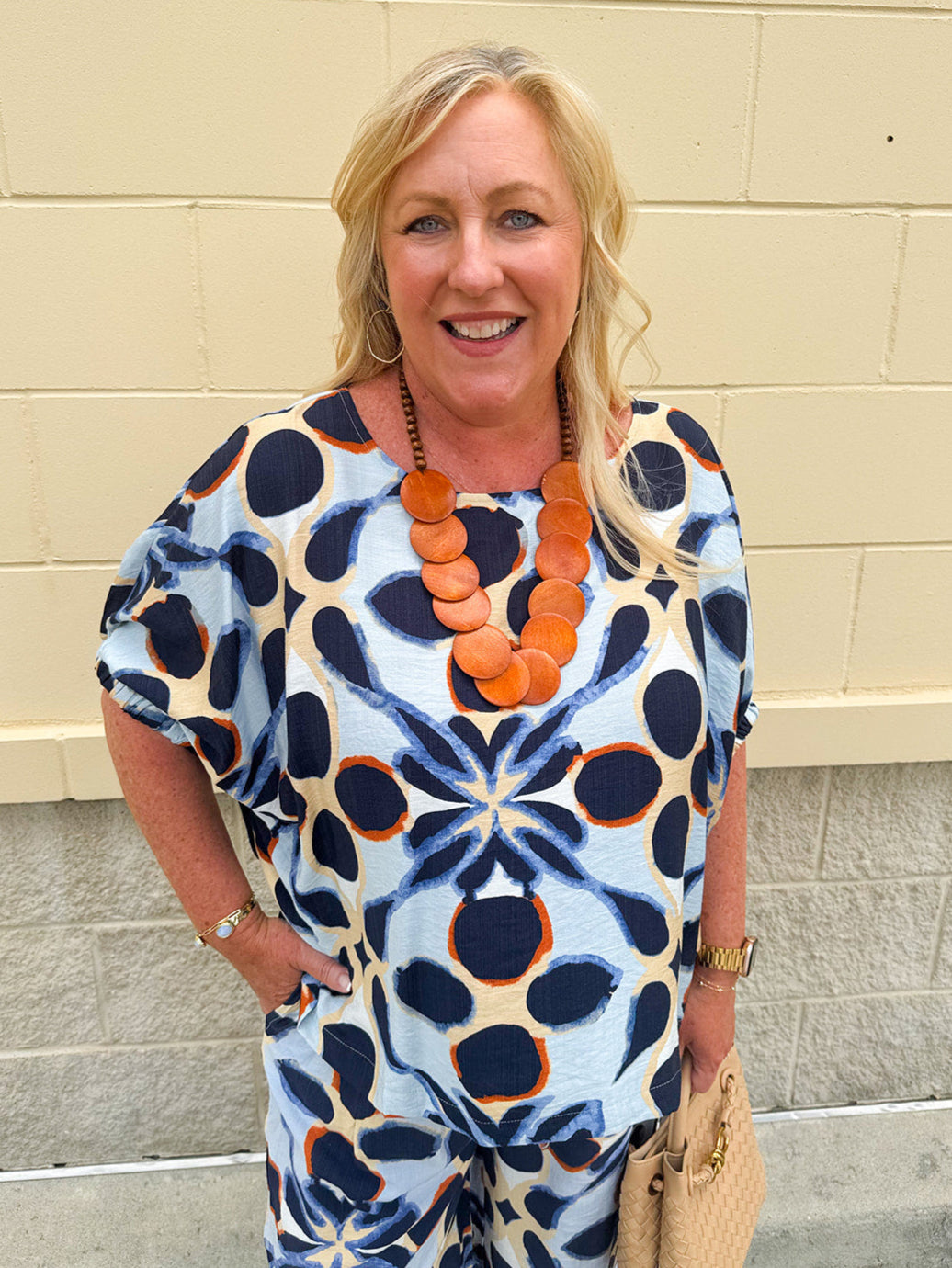 Printed short sleeve top in light blue with colorful indigo, orange, and yellow pattern, featuring a boat neck and relaxed A-line shape