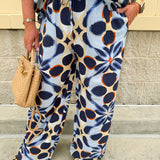 High-waisted printed pants in light blue with indigo, orange, and yellow pattern, featuring smocked waistband and straight leg fit