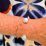Gold cuff bracelet with an oval blue lace agate stone at the center, offering soft blue tones and a serene, elegant feel.