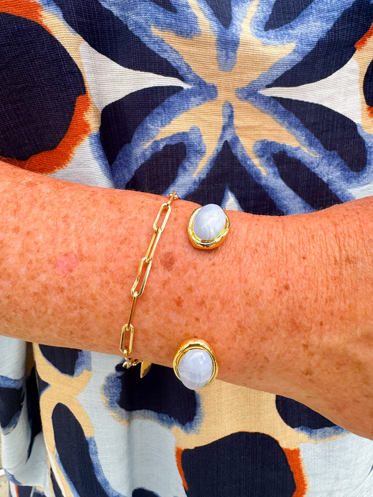 Gold cuff bracelet with an oval blue lace agate stone at the center, offering soft blue tones and a serene, elegant feel.