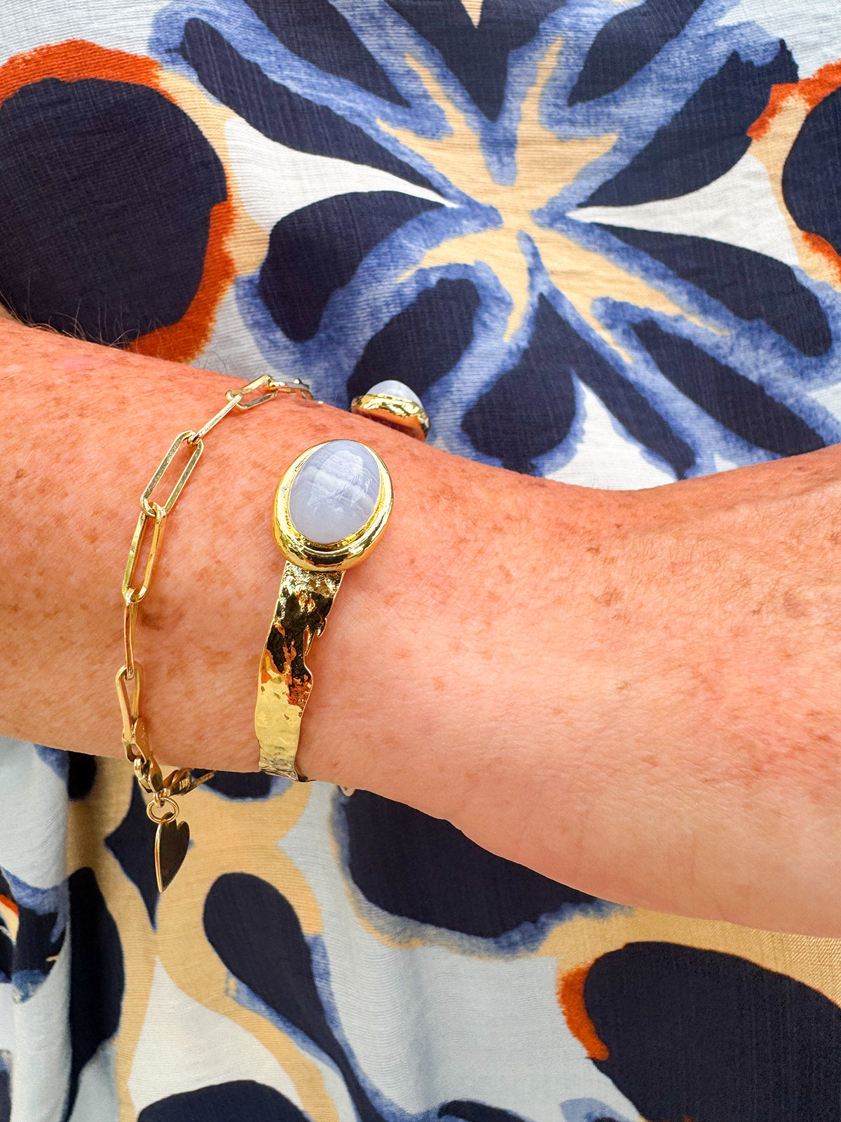 Gold cuff bracelet with an oval blue lace agate stone at the center, offering soft blue tones and a serene, elegant feel.