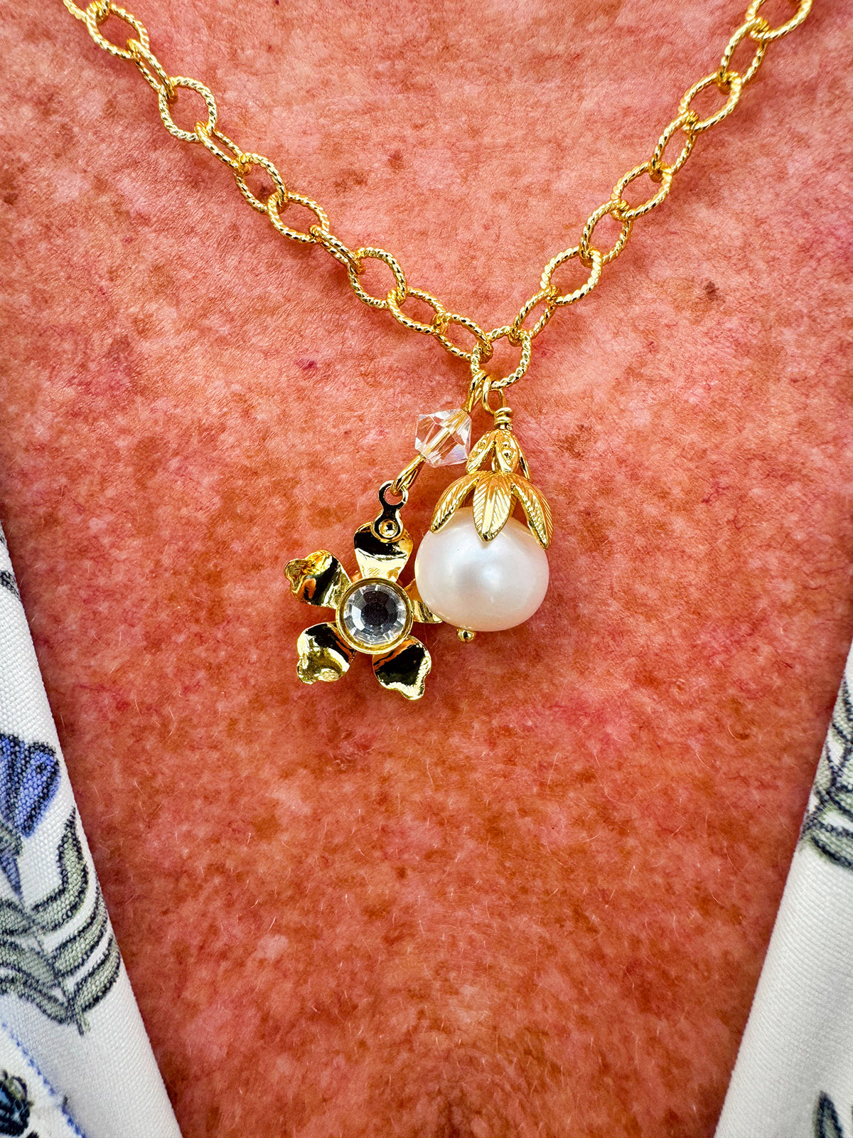 Bright gold-tone small chain link necklace with gold flower crystal pendant and modern pearl pendant.