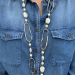 Long necklace with faux pearls and faceted stones draped on a display bust, showcasing layered textures