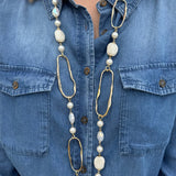 Long necklace with faux pearls and faceted stones draped on a display bust, showcasing layered textures