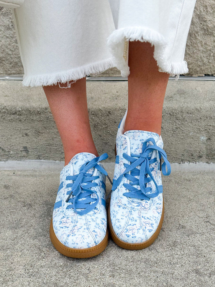 Blue floral sneakers with blue laces, side stripes, and tan rubber sole