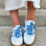 Blue floral sneakers with blue laces, side stripes, and tan rubber sole