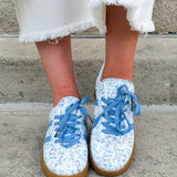 Blue floral sneakers with blue laces, side stripes, and tan rubber sole