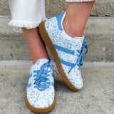 Blue floral sneakers with blue laces, side stripes, and tan rubber sole